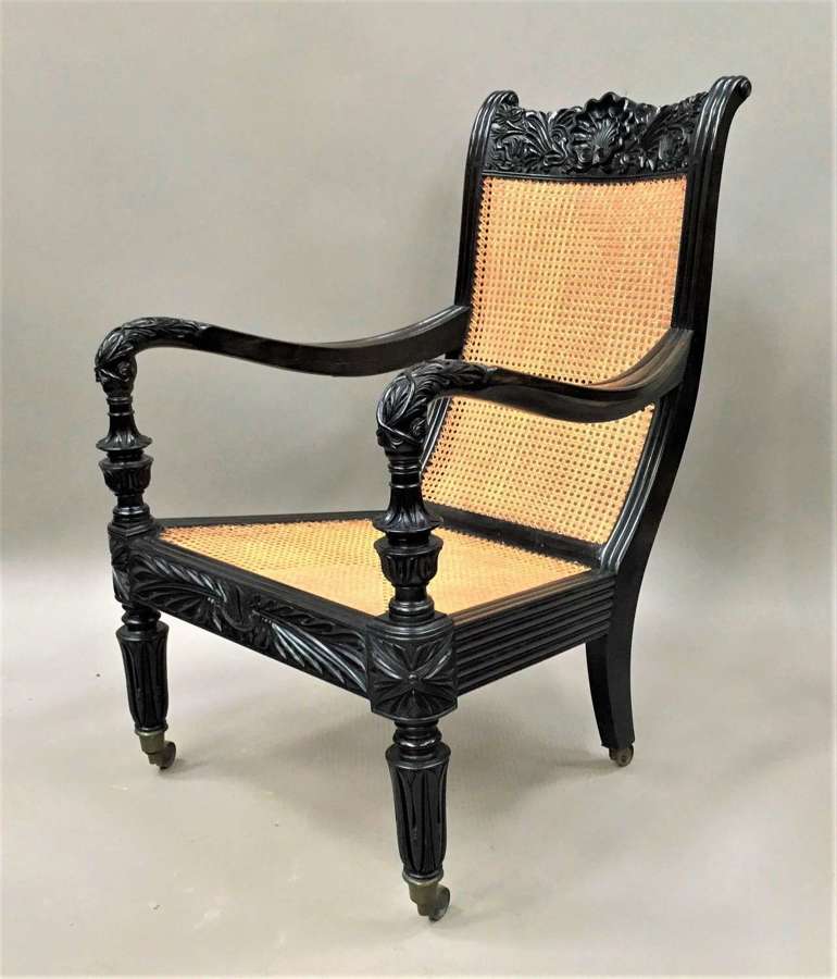C19th Indian carved ebony open arm library chair
